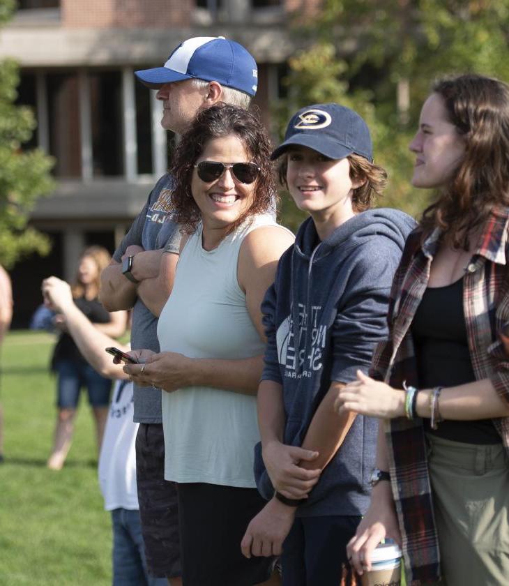 Student and parents laughing outdoors at a campus event 